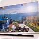 Flat-screen TV displaying a painting-style image of people by the sea with boats and flags.