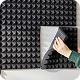 Person installing black acoustic foam panels on a wall.
