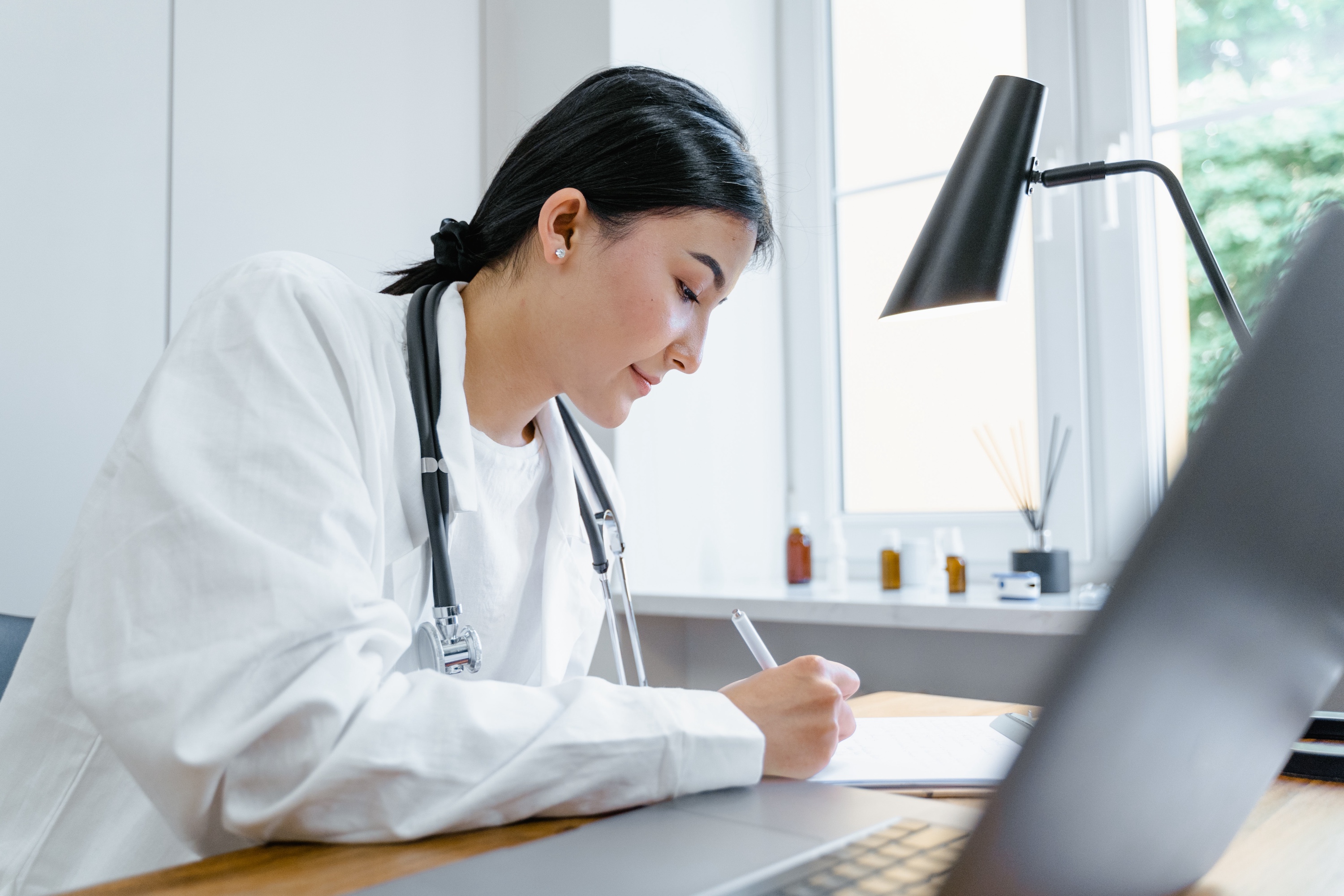 Female doctor writing notes at her desk.
