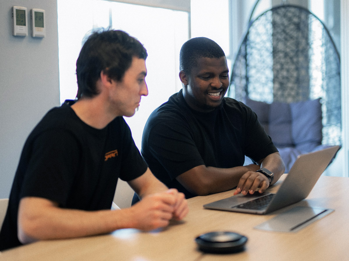 Two engineers collaborate looking at a laptop.