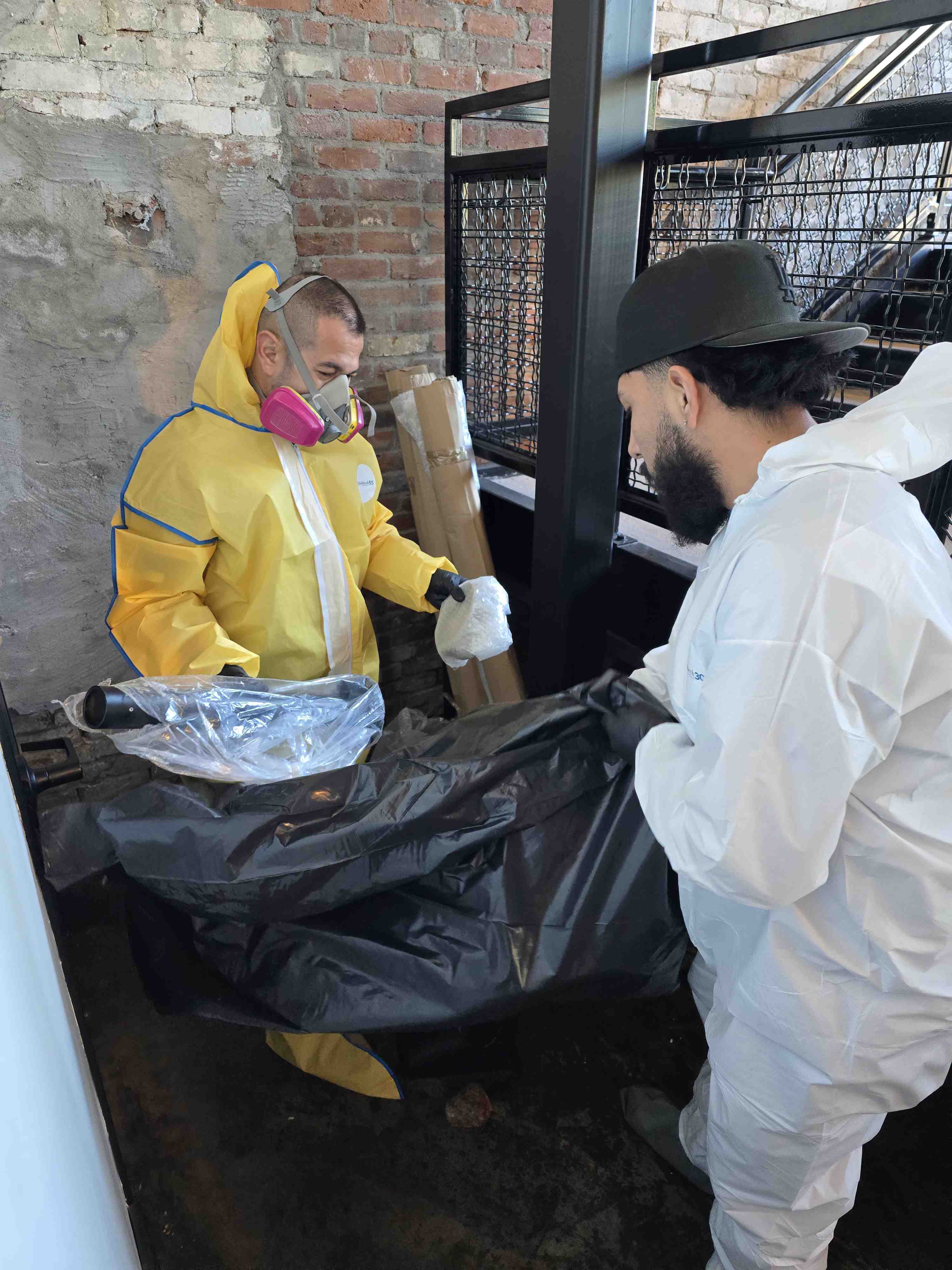 Technician in hazmat suit examing water damage residue