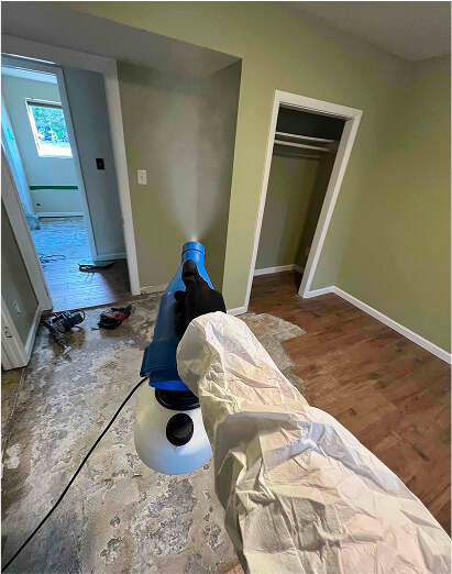 Technician fogging an antimicrobial treatment in a bedroom during mold remediation