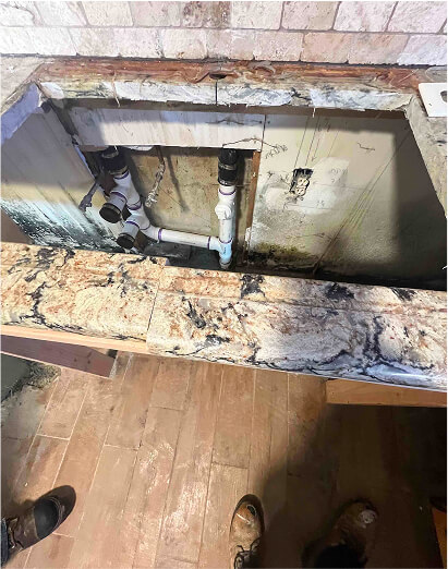 Bathroom vanity opened up to expose moldy plumbing and the wall cavity