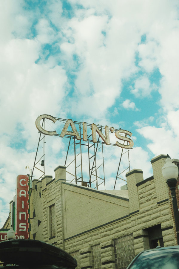 Vintage Cain's sign on top of a beige brick building in Tulsa, Oklahoma under a partly cloudy blue sky.