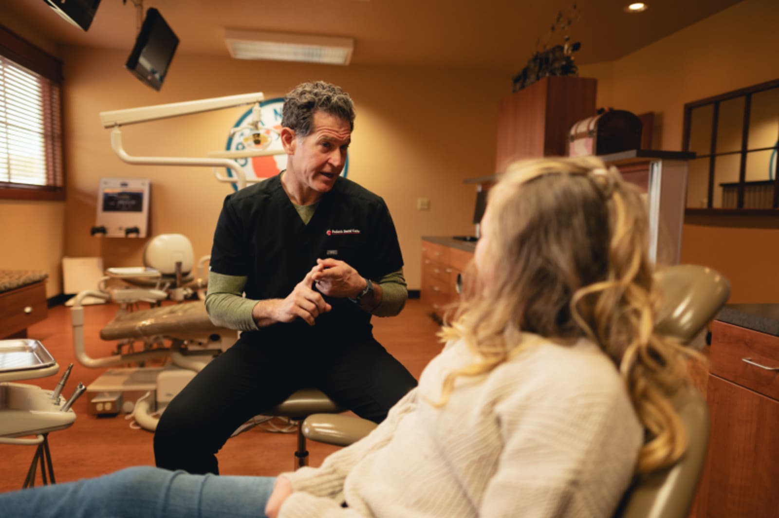 Dentist in black scrubs discussing treatment with a parent and young child
