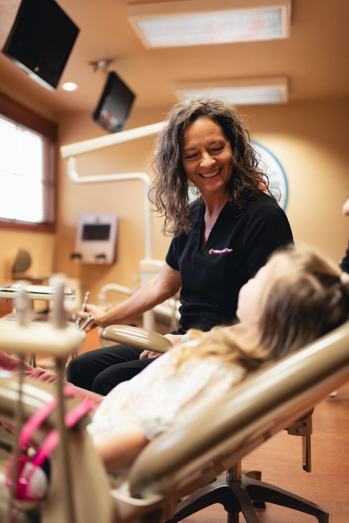 Pediatric dentist examining a young patient in the treatment chair during a dental consultation