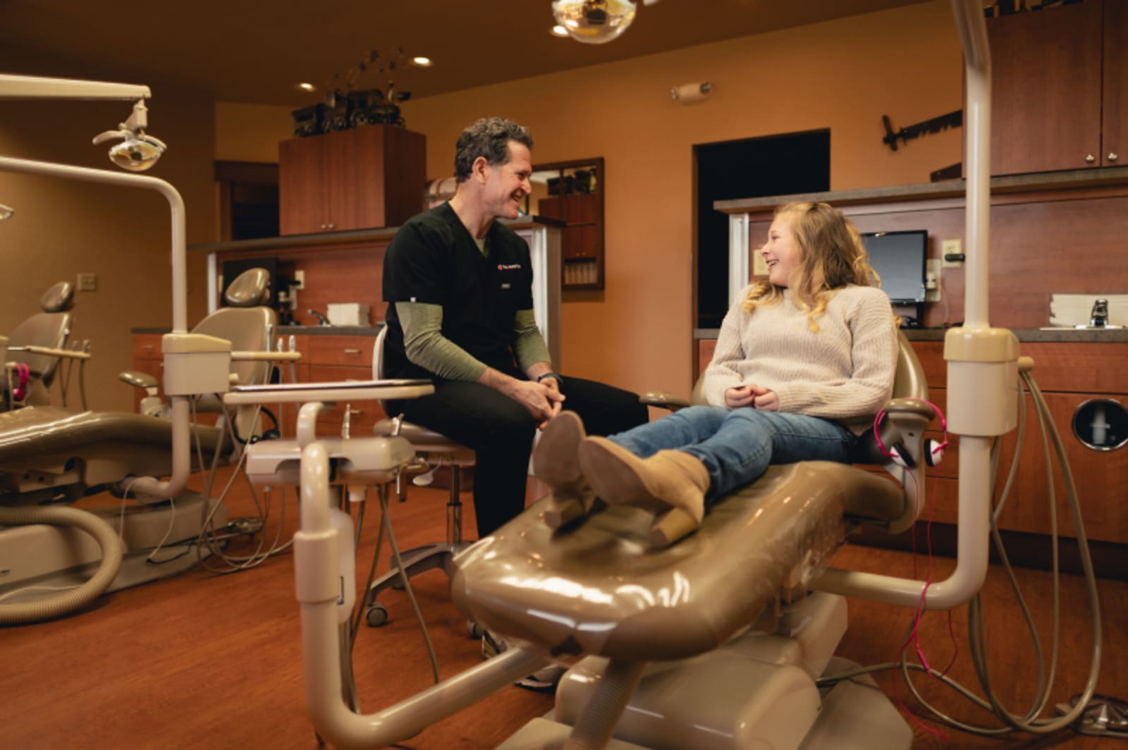 Pediatric dentist performing an oral examination on a young patient in the treatment chair