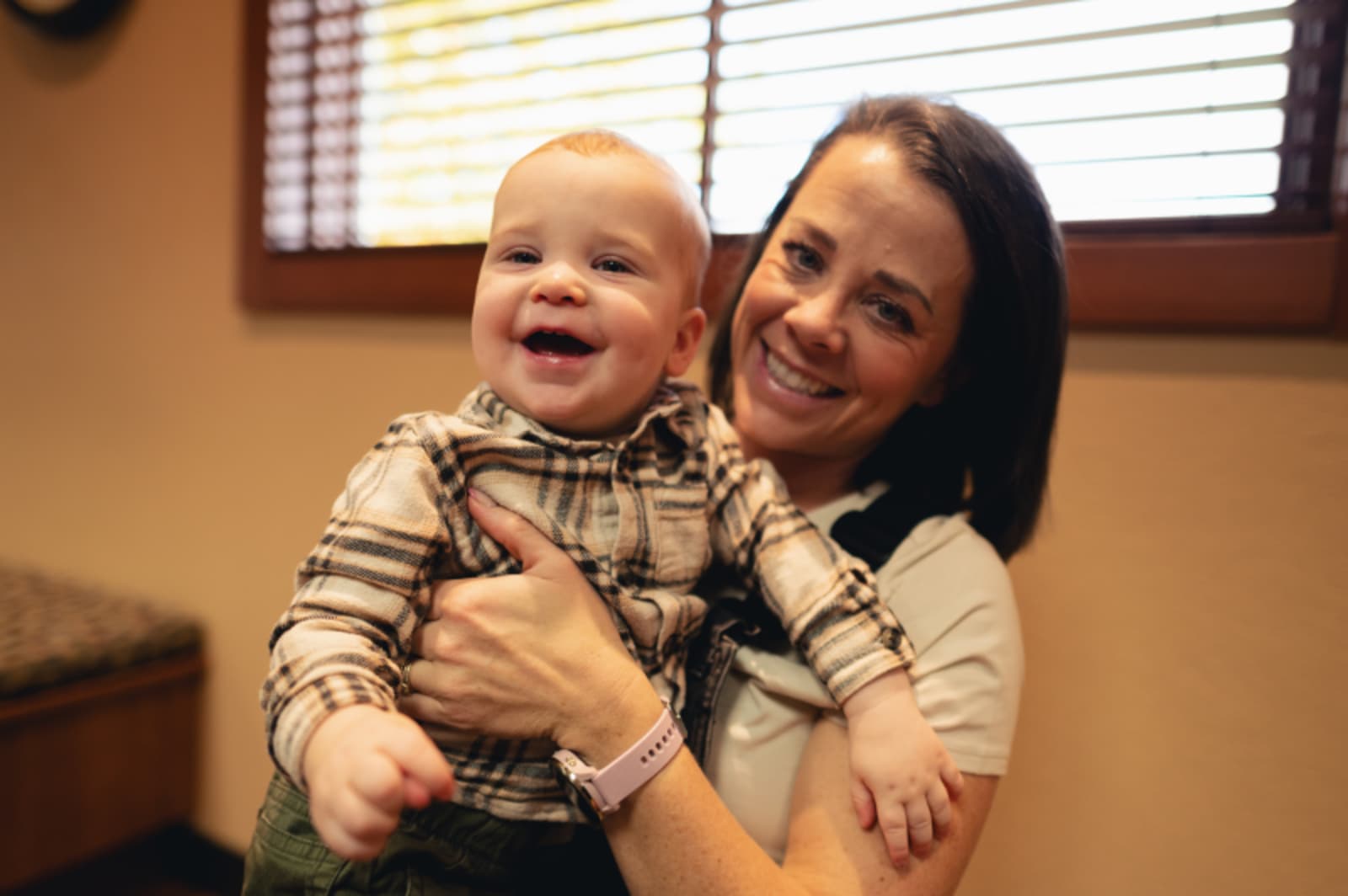 Mother smiling while holding happy toddler during dental visit