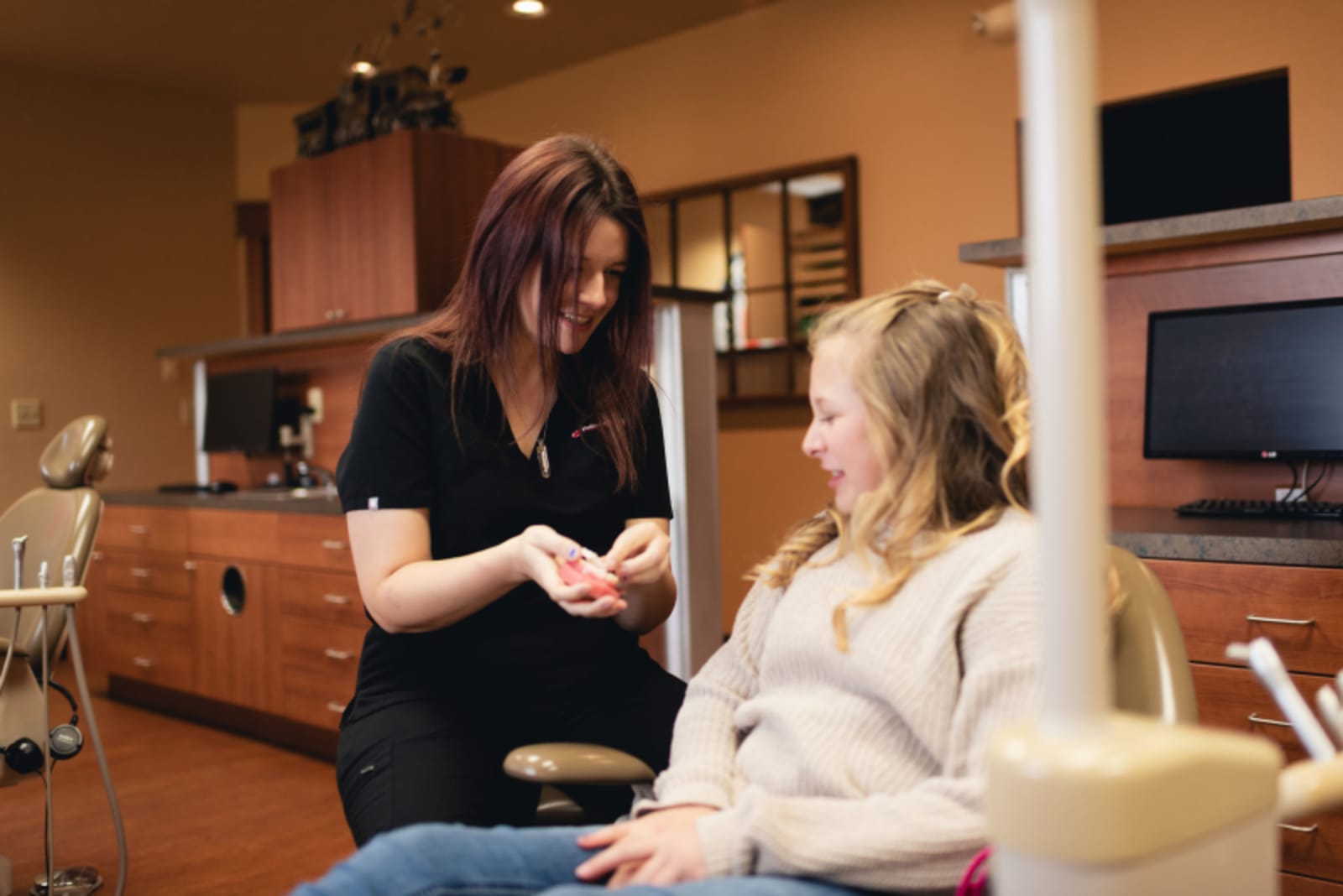 Female dentist discussing treatment plan with young patient in dental office.