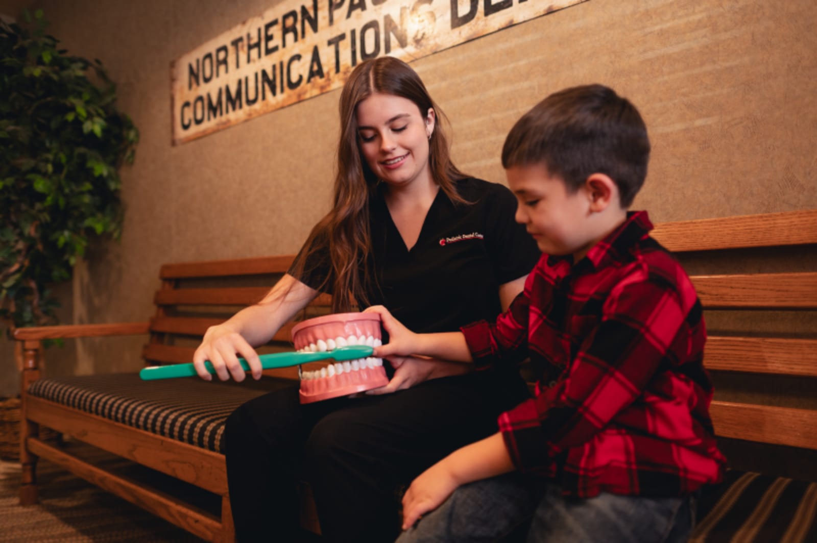 Dentist showing a toothbrush to a young boy, demonstrating proper dental care technique