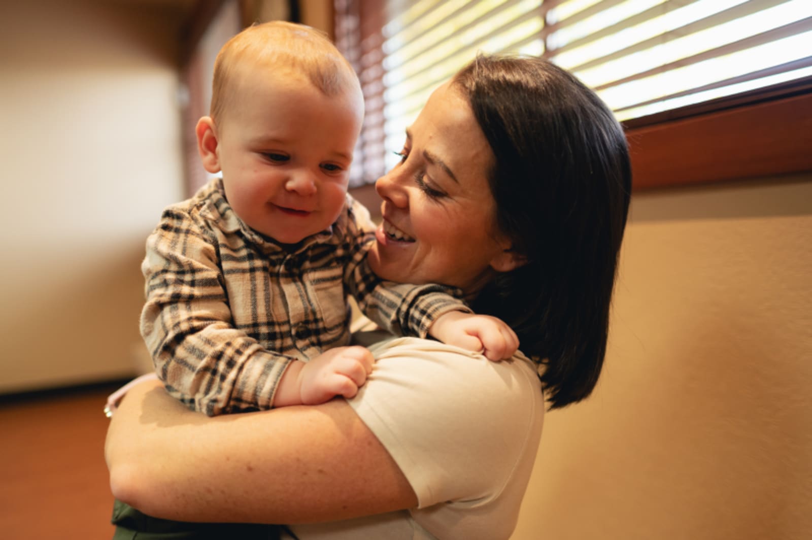 A mom holds and smiles at her young child during an examination.
