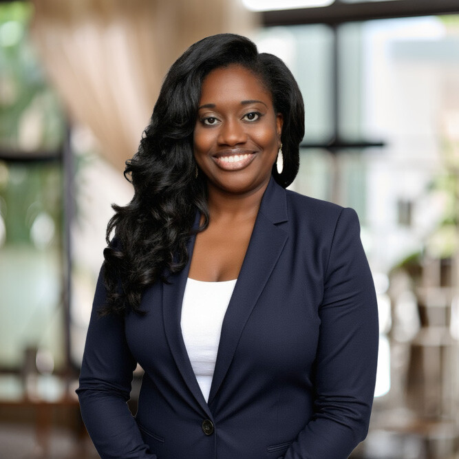 Smiling woman with long black hair wearing navy blazer and white top in a bright indoor space.
