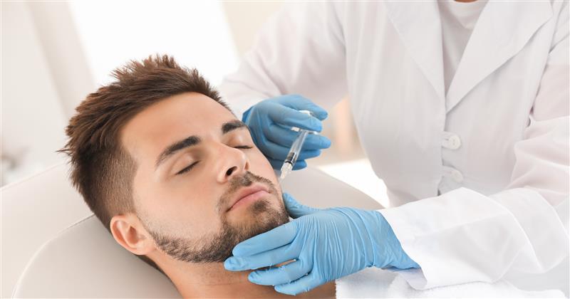 Man with eyes closed receiving an injection in his chin from a gloved medical professional.