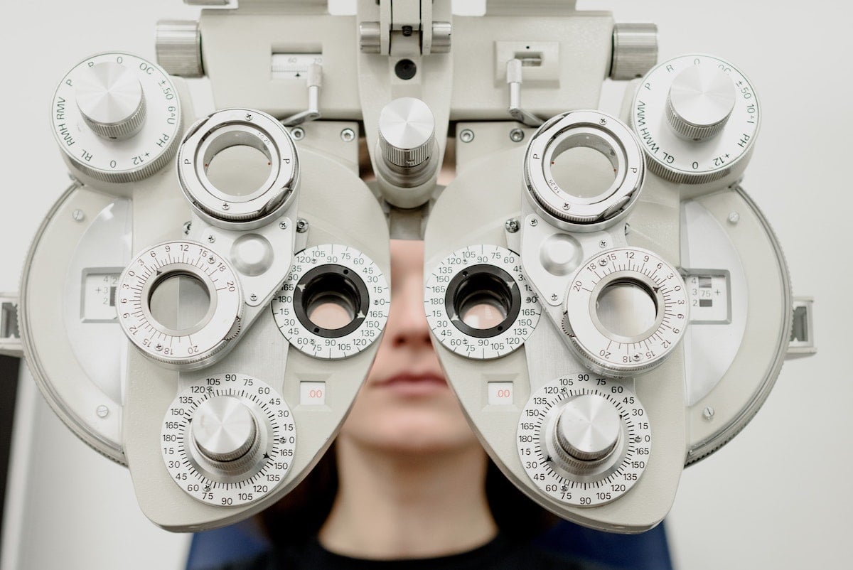 Close-up of an ophthalmic eye test device with a blurred face of a person behind it.