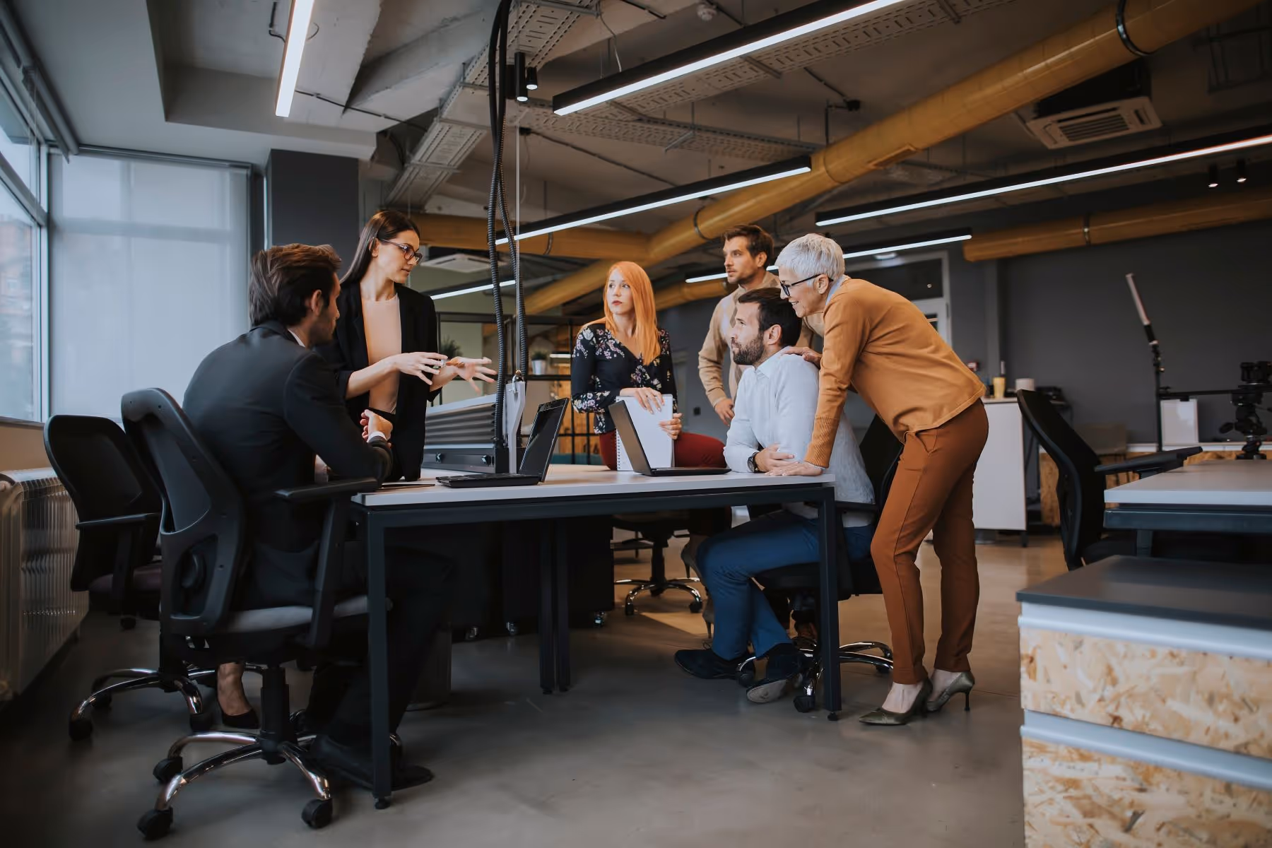 Group of colleagues gathered by a desk conversing together