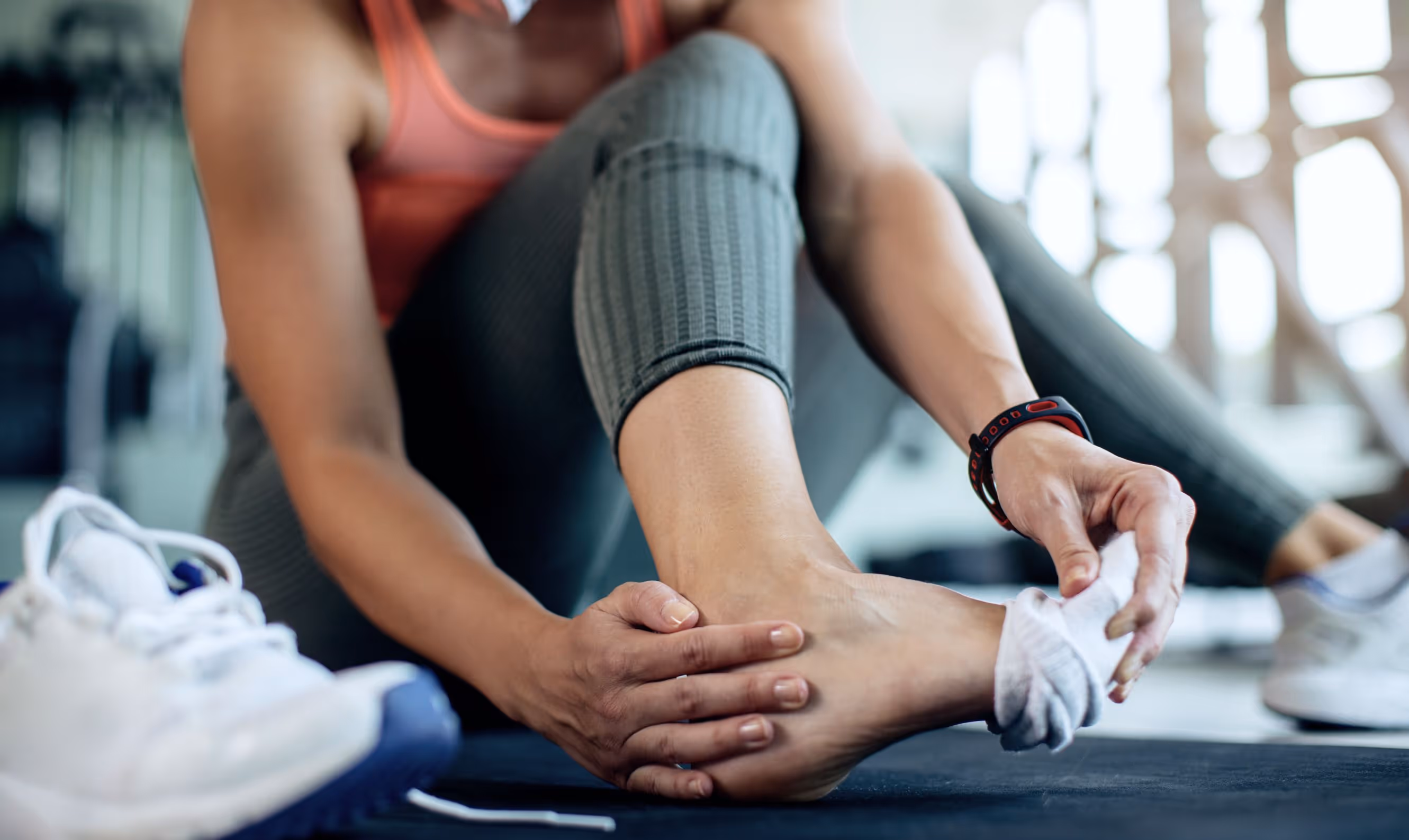 Woman in Los Angeles sits on floor, showing ankle swelling, bruising, and pain, indicating sprain symptoms.