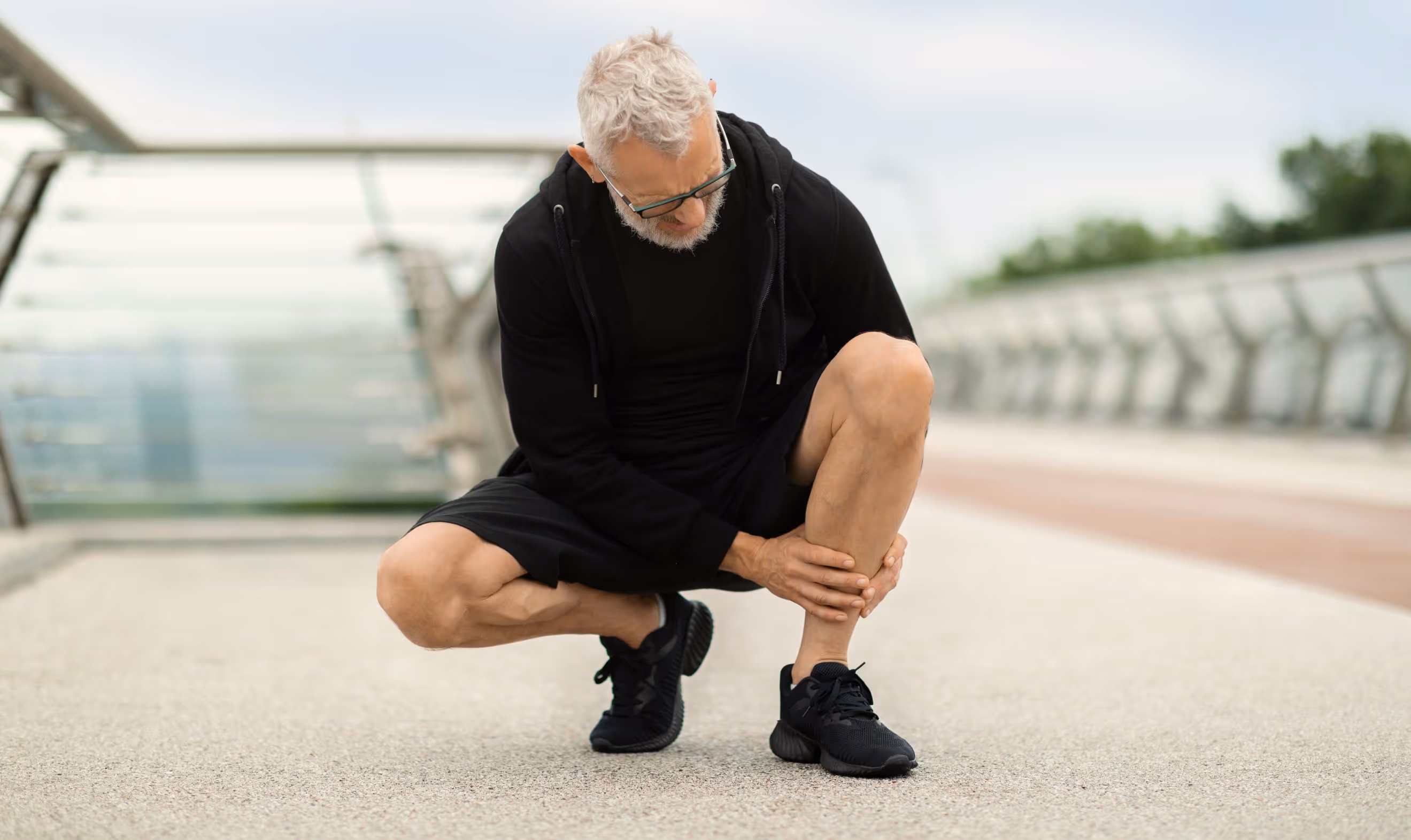 Man in Los Angeles kneeling, experiencing dull, aching pain, shin tenderness, and mild swelling.