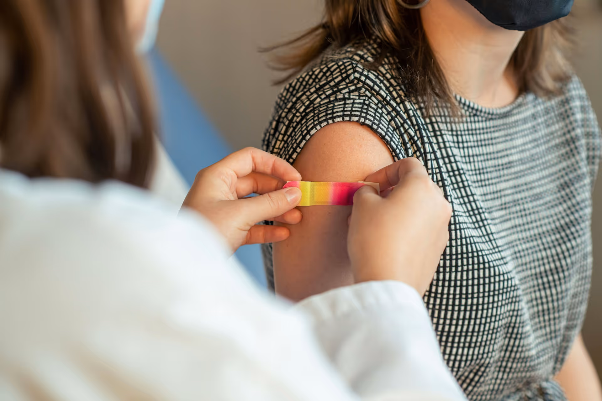 A nurse taking care of a patient, putting a bandage on her arm