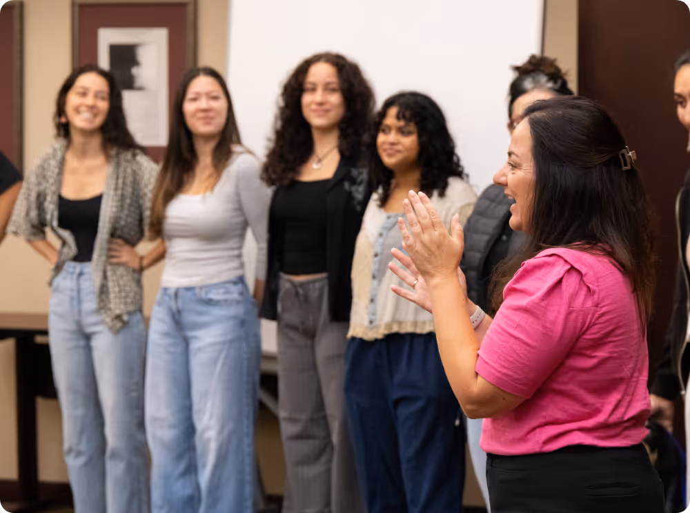 Dr. Manuella Yassa smiling and clapping at NeuroEngage neuroscience education event