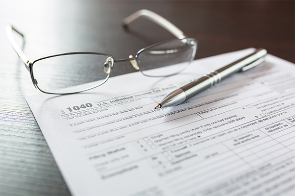 1040 tax return form with a pair of glasses and a pen
