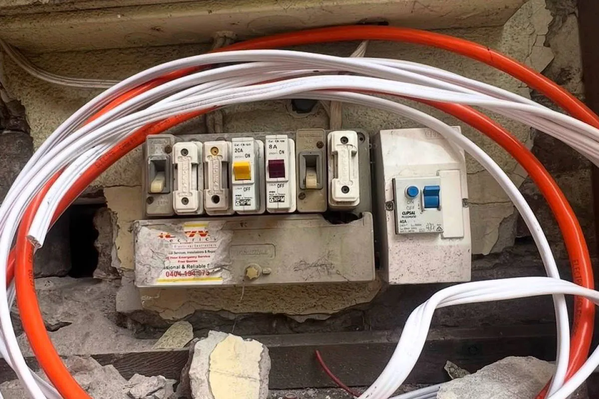 Leichhardt home switchboard before upgrade - exposed ceramic fuses and damaged enclosure during renovation
