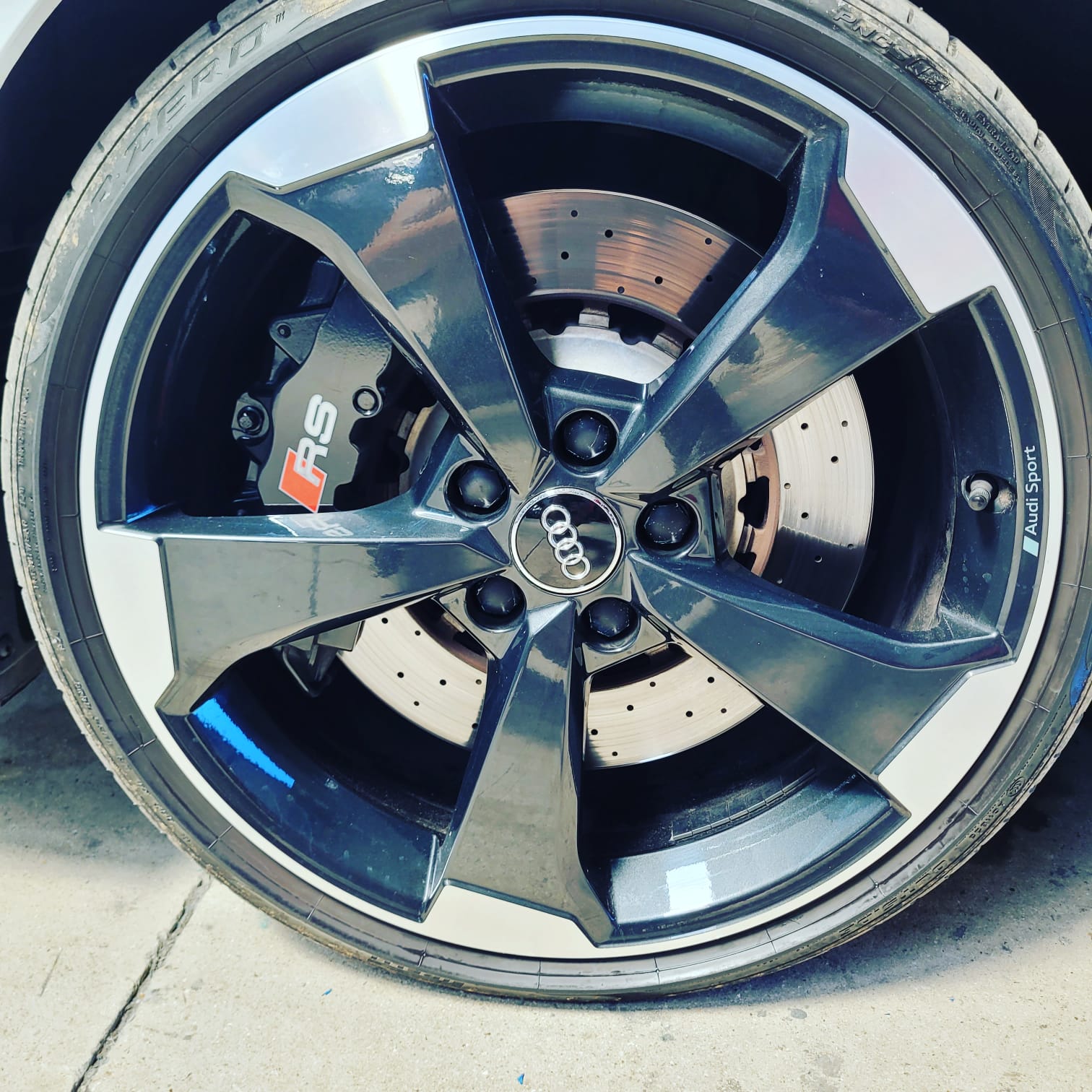 Jante noire et argentée avec logo Audi au centre, frein sport avec logo RS visible derrière la roue.