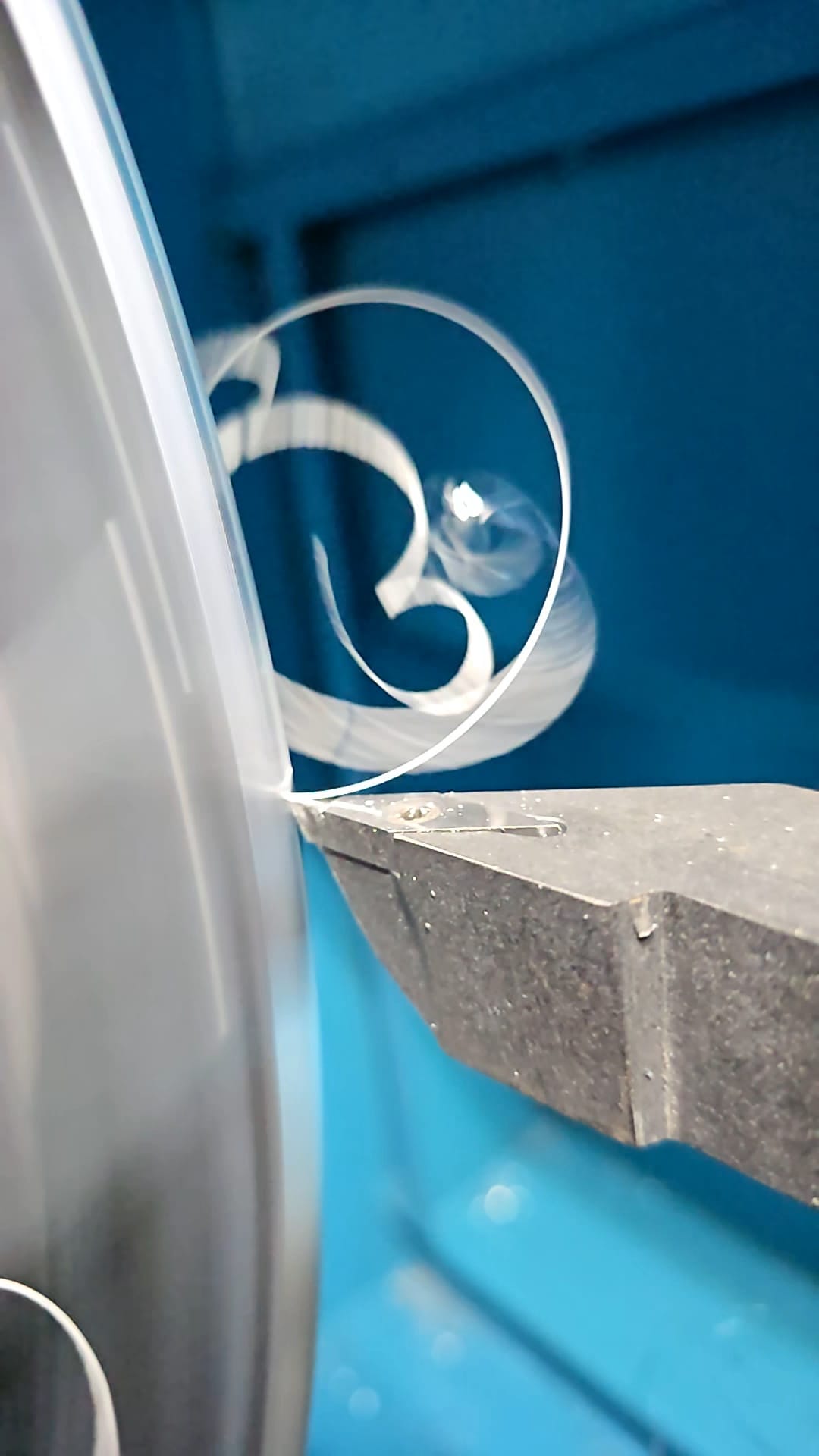 Tournage d'une pièce métallique sur un tour, avec copeaux métalliques en spirale en train de se former.