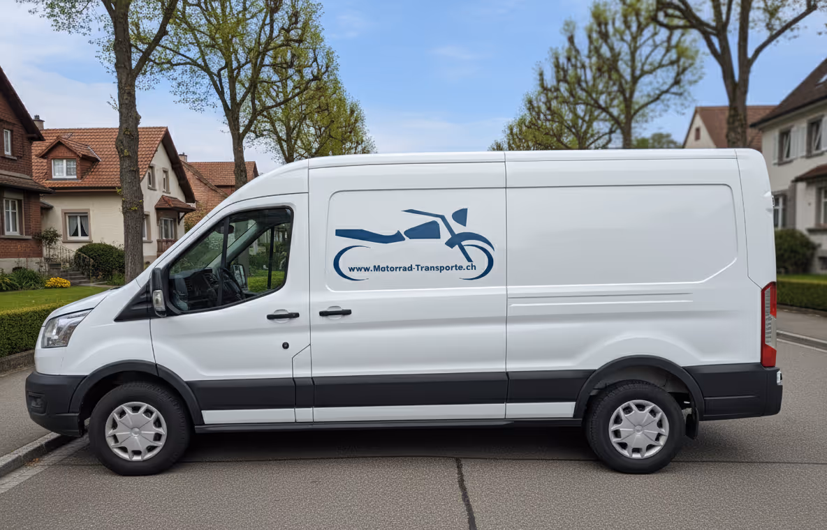Weißer Transporter mit blauem Motorrad-Logo und Text "www.Motorrad-Transporte.ch" auf der Seite, geparkt in einer Wohnstraße.