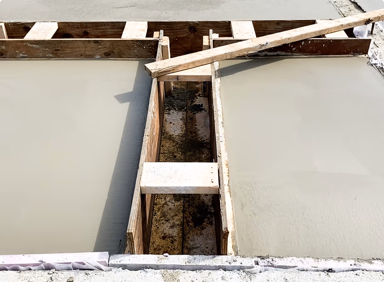 Freshly poured concrete slabs framed with wooden forms and braces at a construction site.