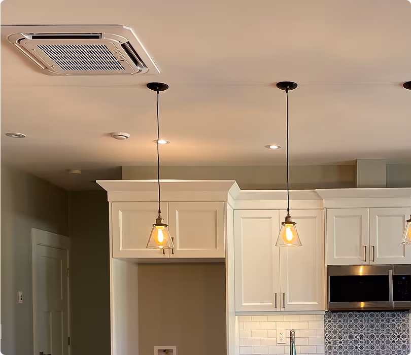 Modern kitchen ceiling with two hanging pendant lights and white cabinets.