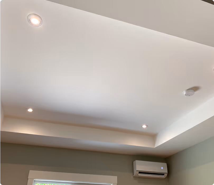 Ceiling with recessed lights and a wall-mounted air conditioning unit showing a digital display of 20 degrees.