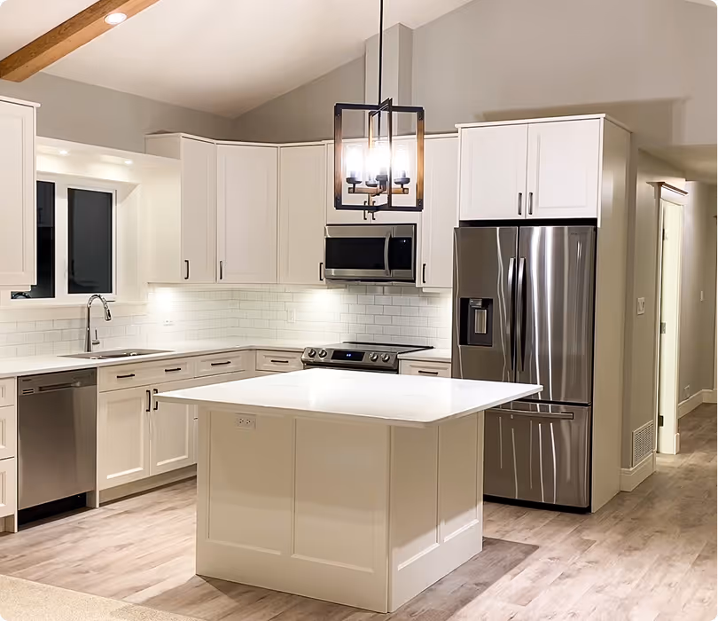 Modern kitchen with white cabinets, stainless steel appliances, a large white island, and a pendant light fixture.