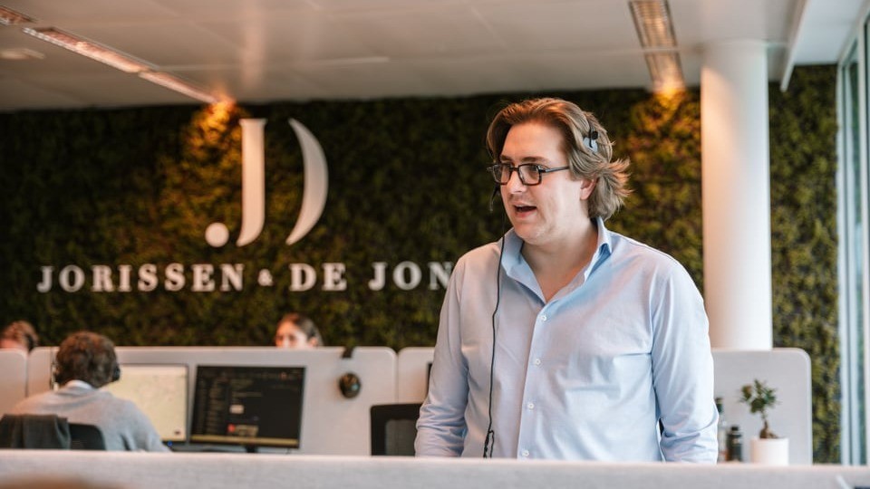 Man met headset aan het werk in modern kantoor van Jorissen & De Jonck, gespecialiseerd in finance rekrutering