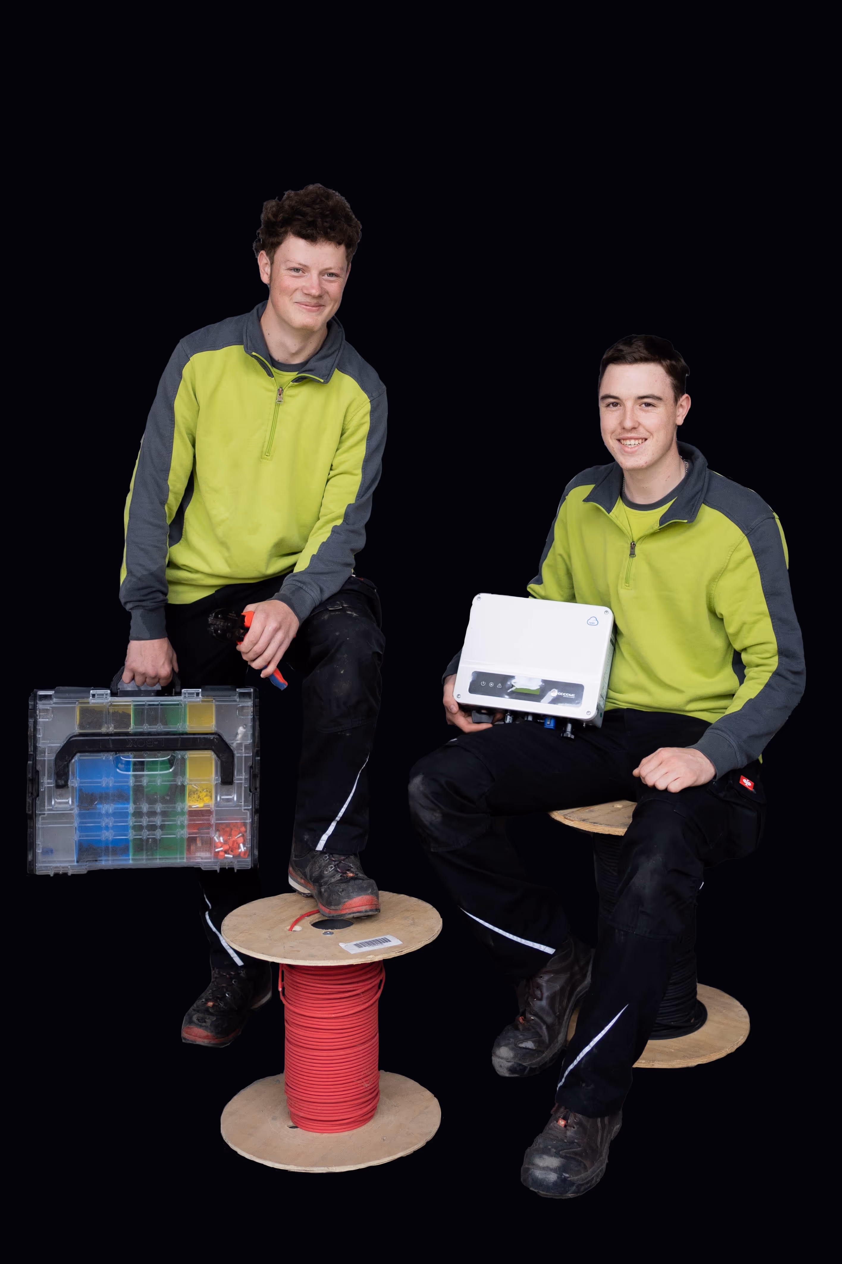 Zwei Techniker in gelb-grauen Jacken mit Kabelbox und Elektrogerät