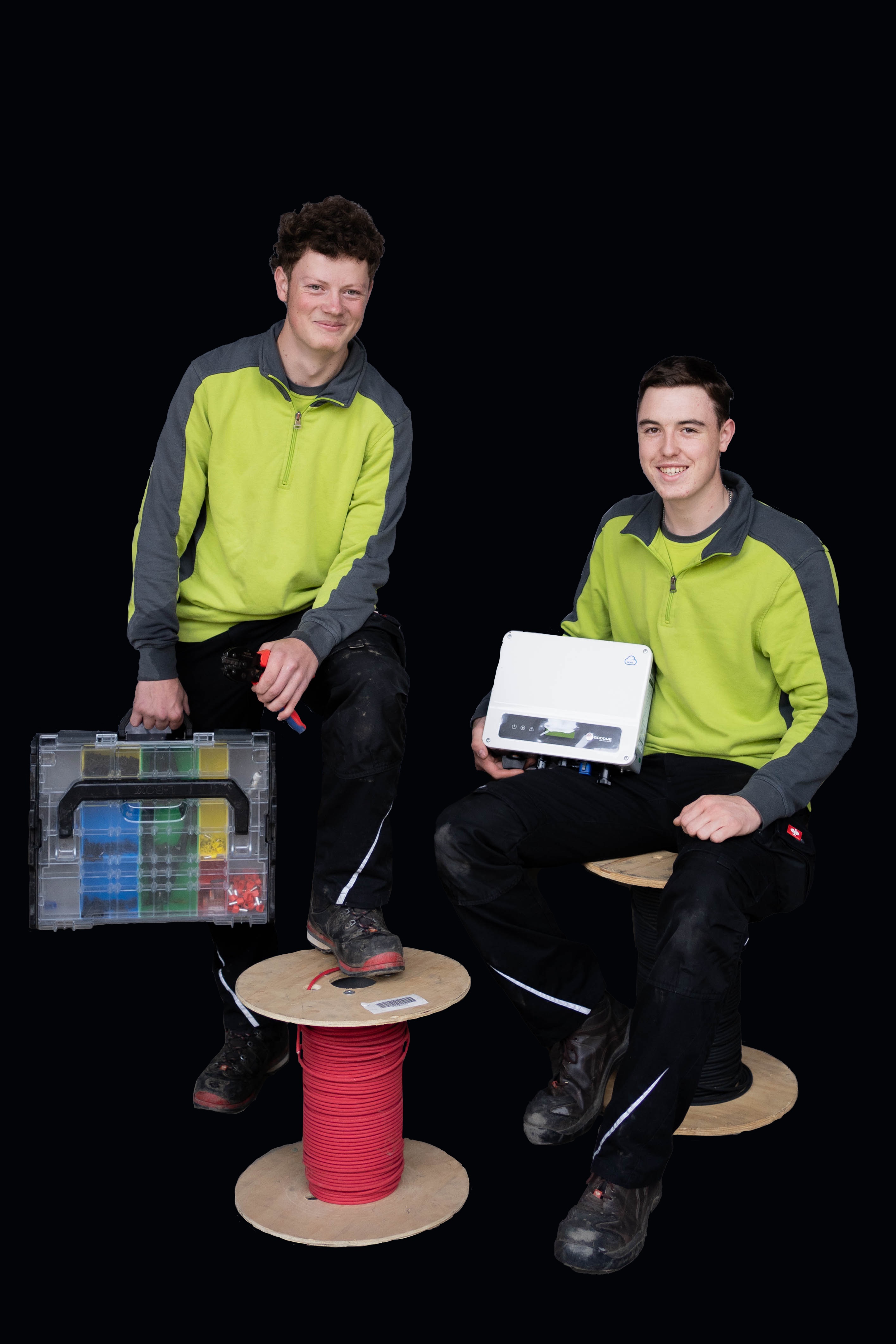 Zwei Techniker in gelb-grauen Jacken mit Kabelbox und Elektrogerät