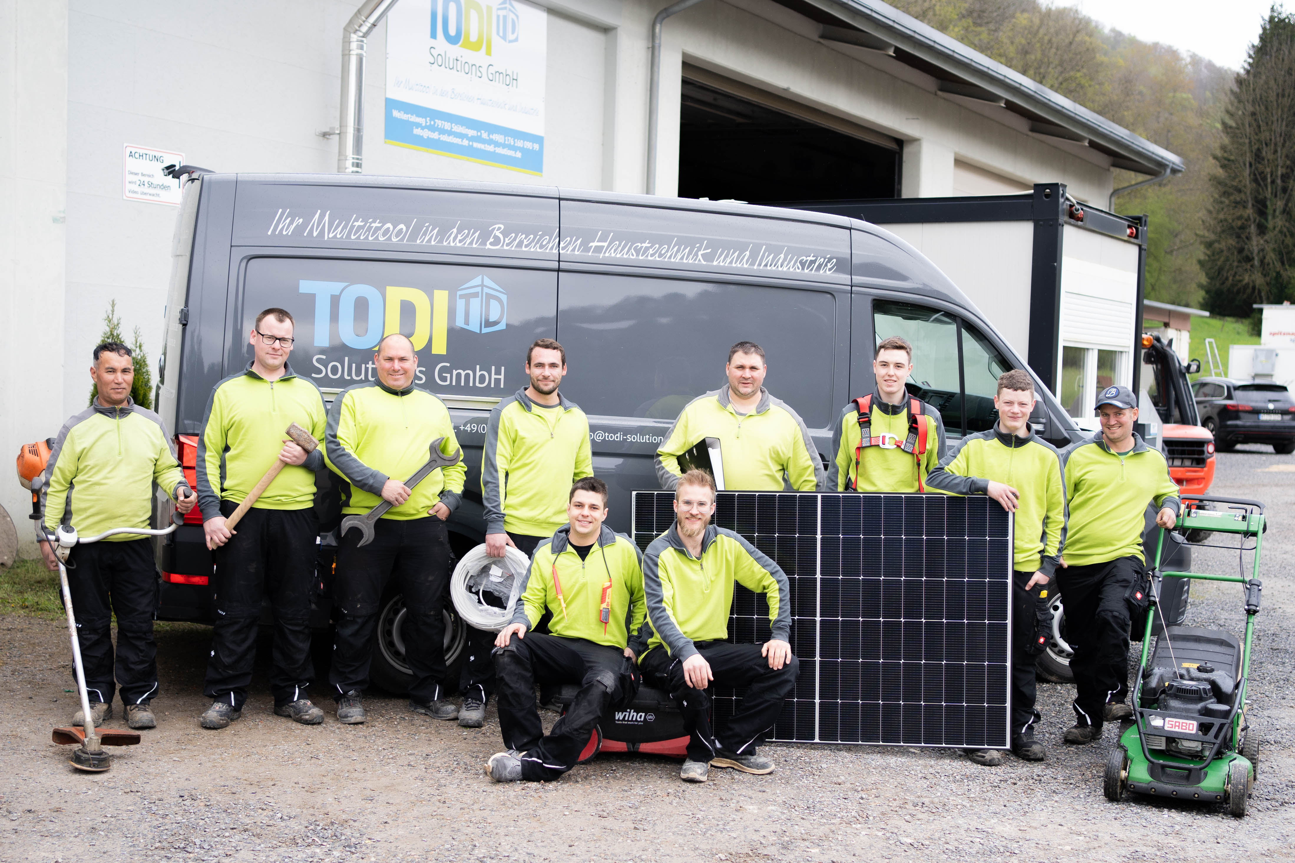 TODI Solutions GmbH Team in gelben Hemden mit Solarpanel und Arbeitsgeräten