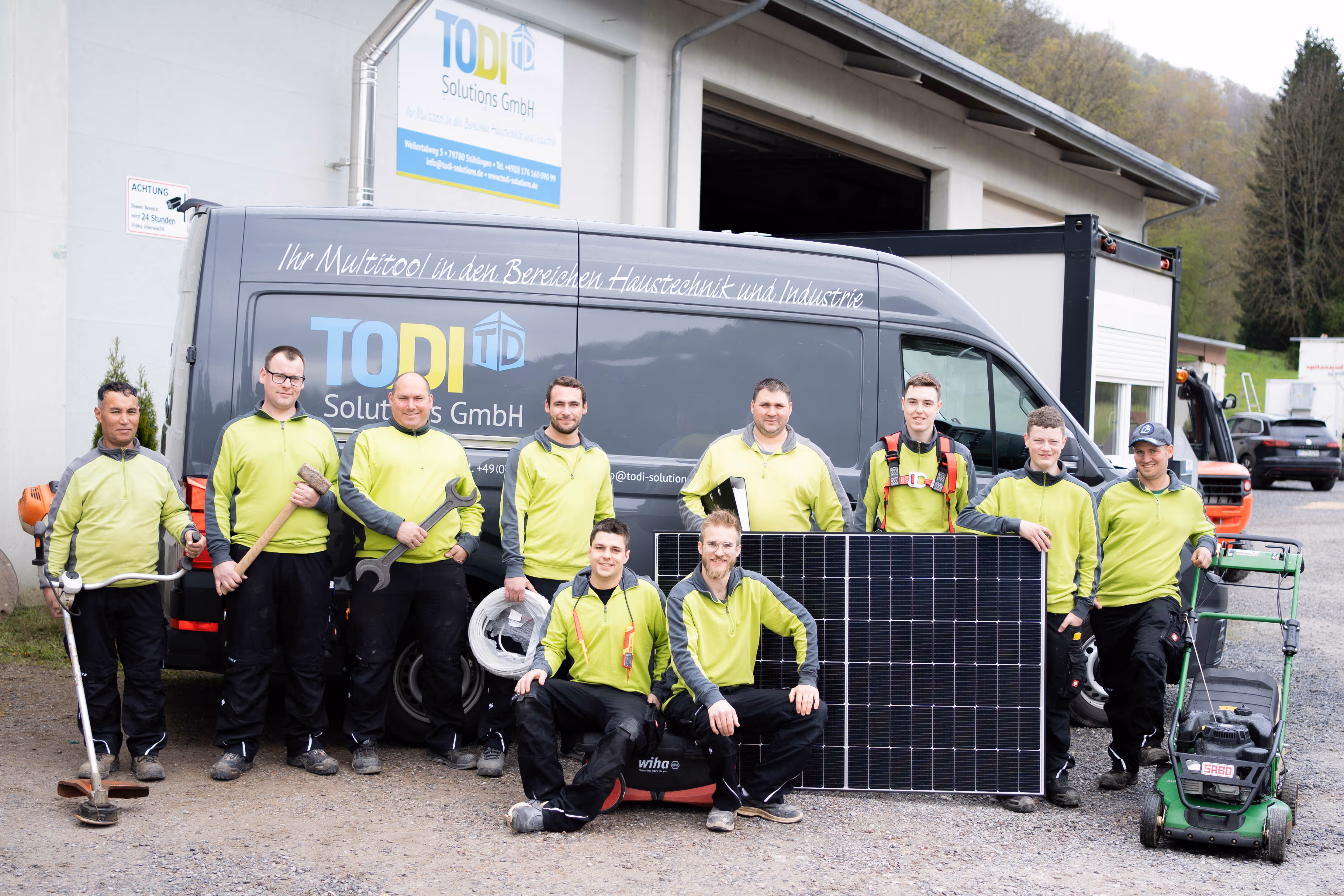 Acht Mitarbeiter der TODI Solutions GmbH mit Firmenwagen und Solarmodul