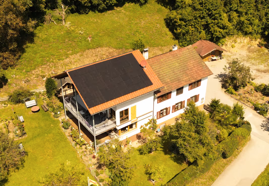 Luftaufnahme eines zweistöckigen weißen Hauses mit Balkon im grünen Garten