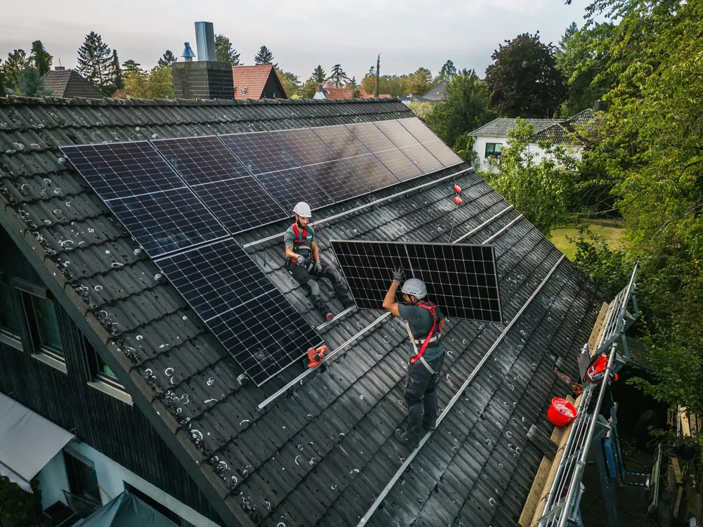 Arbeiter installieren Solarzellen auf dem Dach eines Wohnhauses
