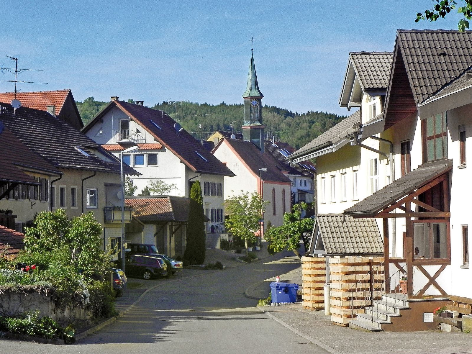 Mit Schnee bedecktes Dach mit Solarzellen an sonnigem Wintertag neben schneebedeckten Tannenbäumen.