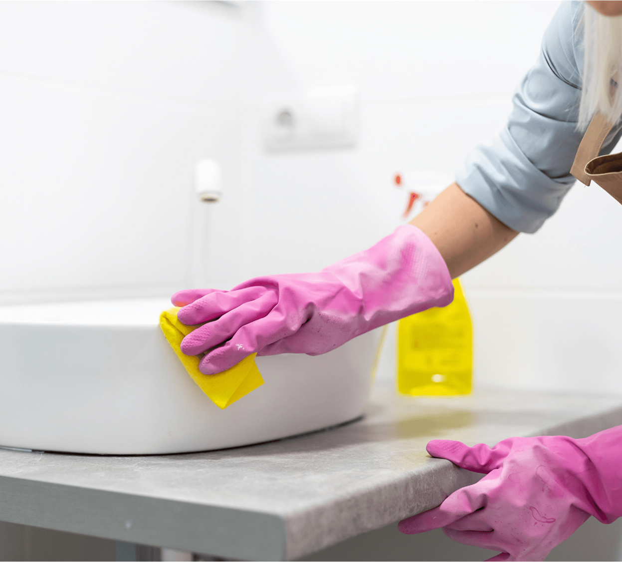 Person in pink gloves scrubbing a bathroom sink