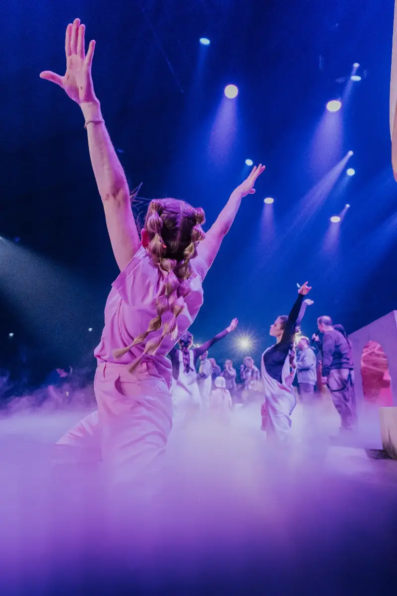 Tänzer auf der Bühne in einer dynamischen Pose mit Nebel und bunten Lichtern