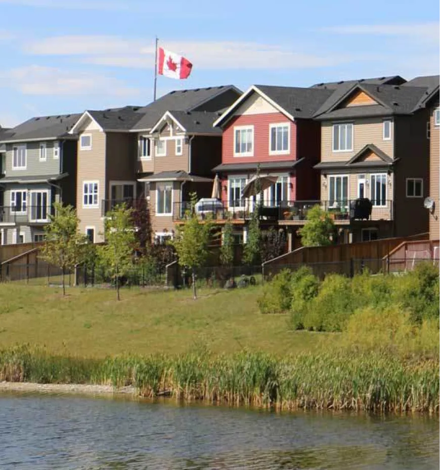 Row of houses with Canadian flag by lakeside.