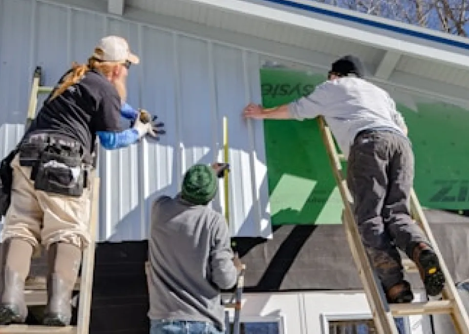 Workers installing siding on a house.