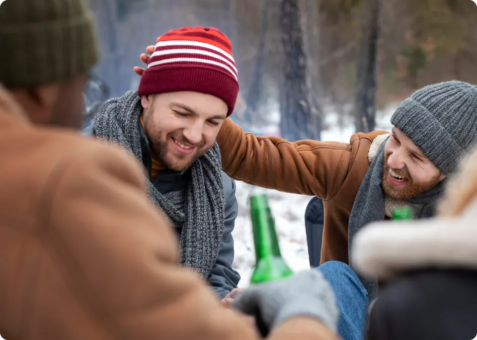 Friends laughing outdoors in winter clothing.