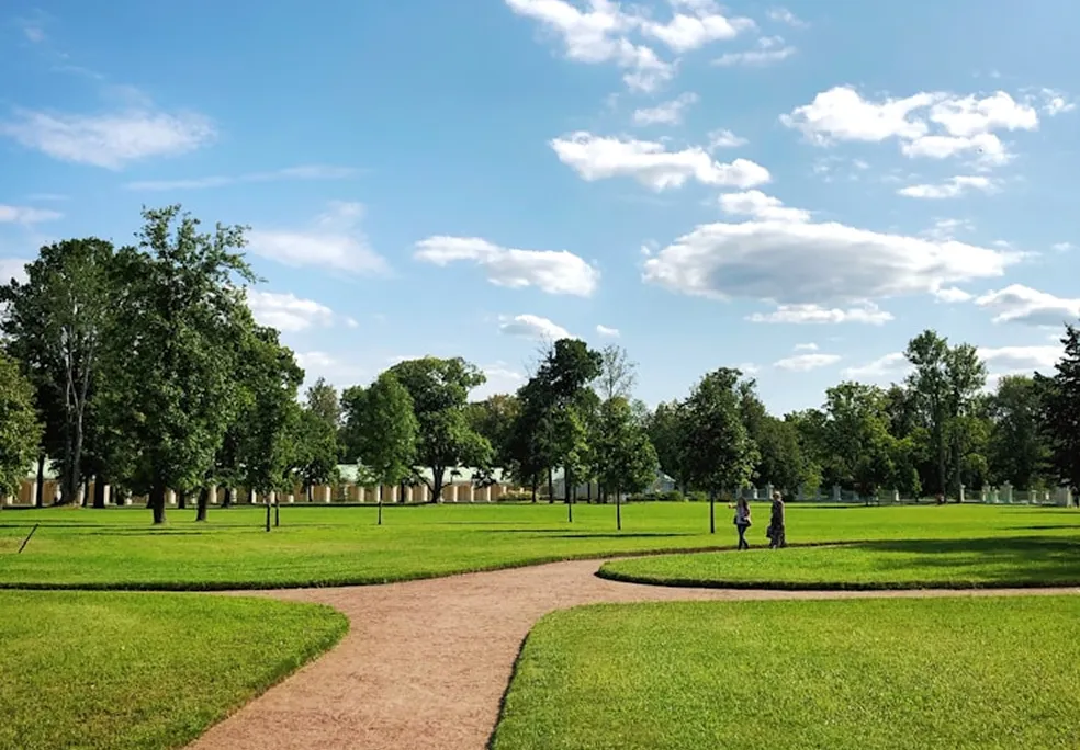 Park with green grass, trees, and a dirt pathway.