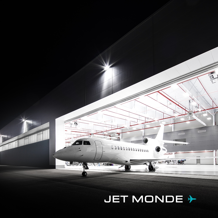 Jet d'affaires moderne stationné dans un hangar illuminé, symbolisant le progrès technique sur cinq décennies.