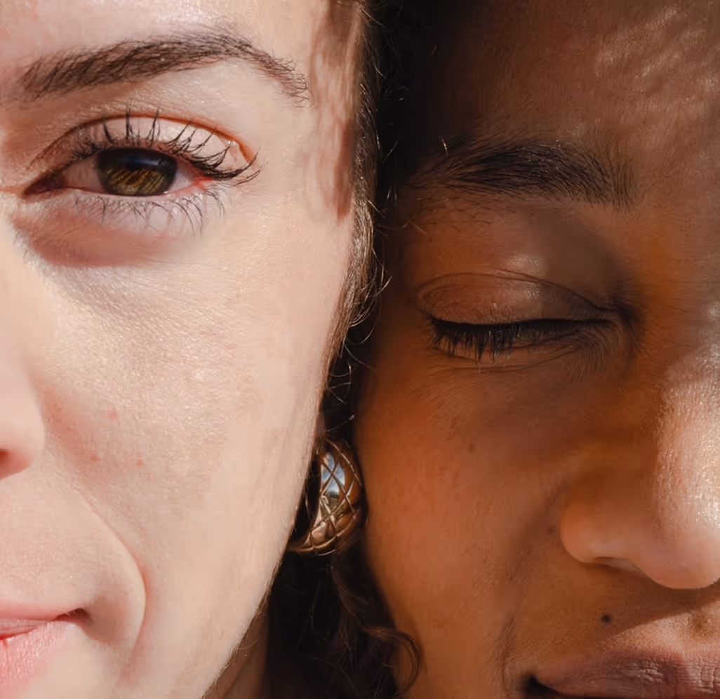 Close-up of two women's faces side by side, one with an open eye and the other with closed eyes, highlighting skin textures and natural features.