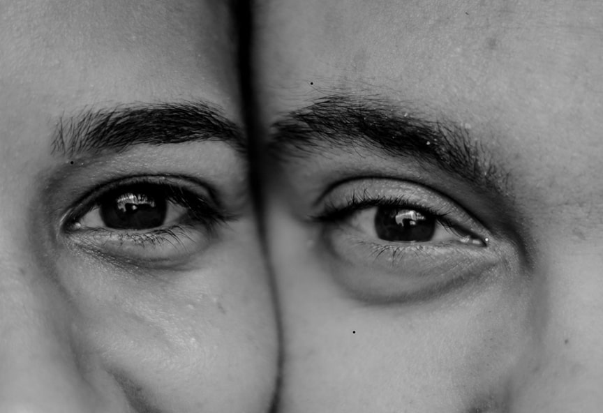 Close-up black and white photo of two people’s eyes and eyebrows touching side by side.