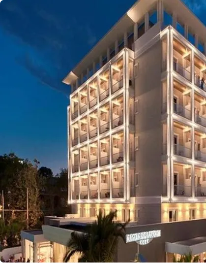 Edificio moderno a più piani illuminato di sera con balconi e finestre illuminate.